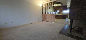 Unfurnished living room featuring light carpet and a fireplace
