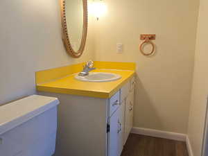 Half bath with a textured ceiling, vanity, and dark wood-style flooring