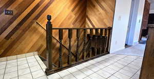 Stairway featuring wood walls and tile patterned floors