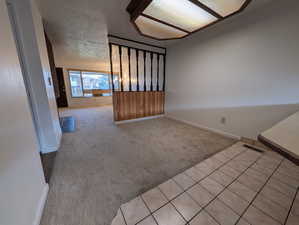 Unfurnished room with light carpet, a textured ceiling, and light tile patterned flooring
