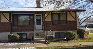 View of front of property with brick siding, a chimney, and entry steps