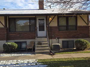 View of front facade featuring brick siding, a chimney, and entry steps
