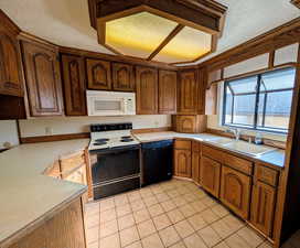 Kitchen featuring electric range, a textured ceiling, light countertops, black dishwasher, and white microwave