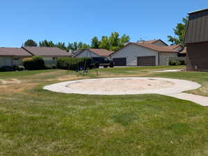 Community greenspace featuring a sand pit with a concrete border, a swing set, and a perimeter of mature trees