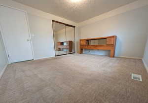 Unfurnished bedroom with a textured ceiling, a closet, and carpet flooring