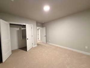Unfurnished bedroom featuring a closet and light carpet
