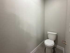 Half bathroom with toilet and tile patterned flooring