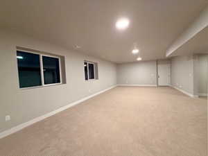 Finished basement with baseboards and light carpet