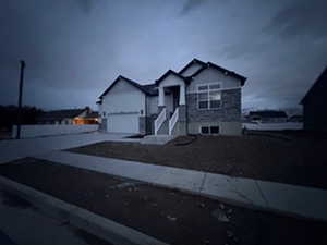 View of front of house with driveway, stone siding, and stucco siding