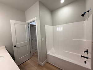 Bathroom with vanity, light wood-style floors, and  shower combination