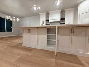 Kitchen with light wood-type flooring, pendant lighting, and open shelves