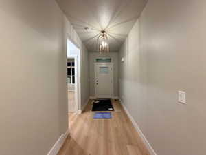 Doorway featuring a chandelier and wood finished floors