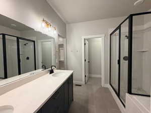 Bathroom featuring a stall shower, double vanity, and dark tile patterned flooring