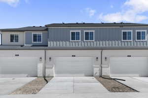 View of front of home with driveway, an attached garage, board and batten siding, and a shingled roof