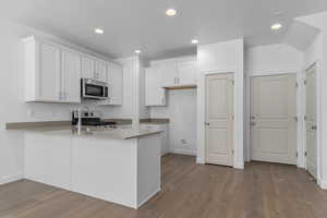 Kitchen featuring white cabinets, appliances with stainless steel finishes, dark wood finished floors, recessed lighting, and a peninsula