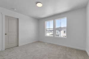 Empty room with light colored carpet and baseboards