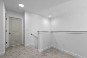 Hall with an upstairs landing, light carpet, and recessed lighting