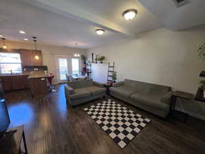 Living area with plenty of natural light, dark wood-style flooring, beamed ceiling, and french doors