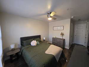 Bedroom featuring dark wood-style flooring, ceiling fan, and a textured ceiling