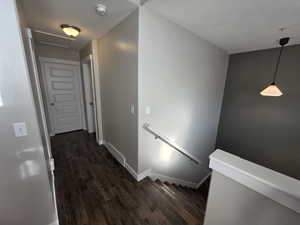 Corridor featuring an upstairs landing and dark wood-type flooring