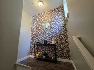 Stairway with wood finished floors, wallpapered walls, and an accent wall
