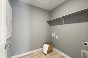 Washroom featuring electric dryer hookup, light wood finished floors, washer hookup, and a textured ceiling