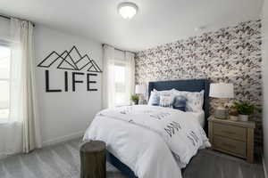 Bedroom with an accent wall, carpet, wallpapered walls, and a textured ceiling