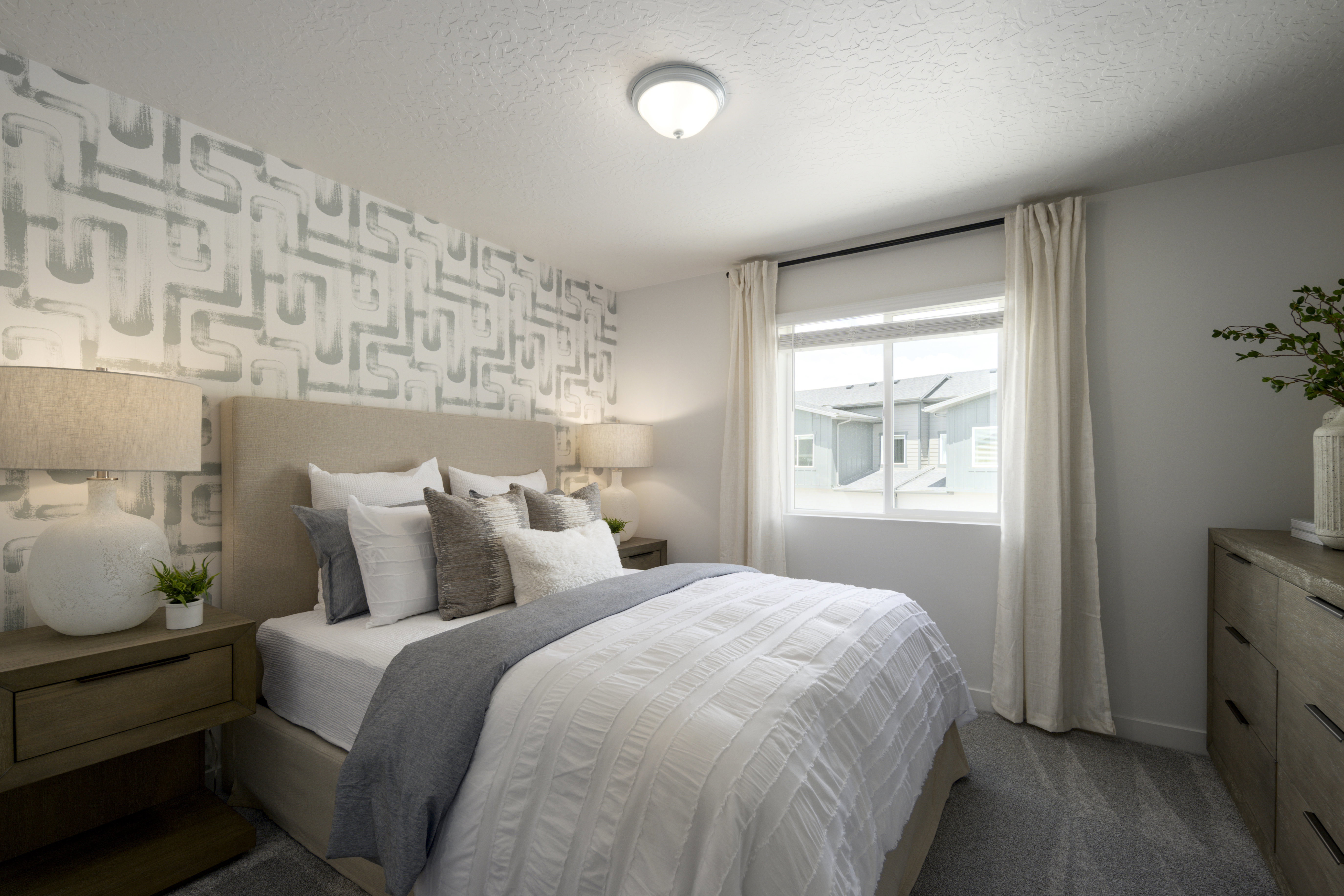 Bedroom with a textured ceiling, wallpapered walls, an accent wall, and dark carpet