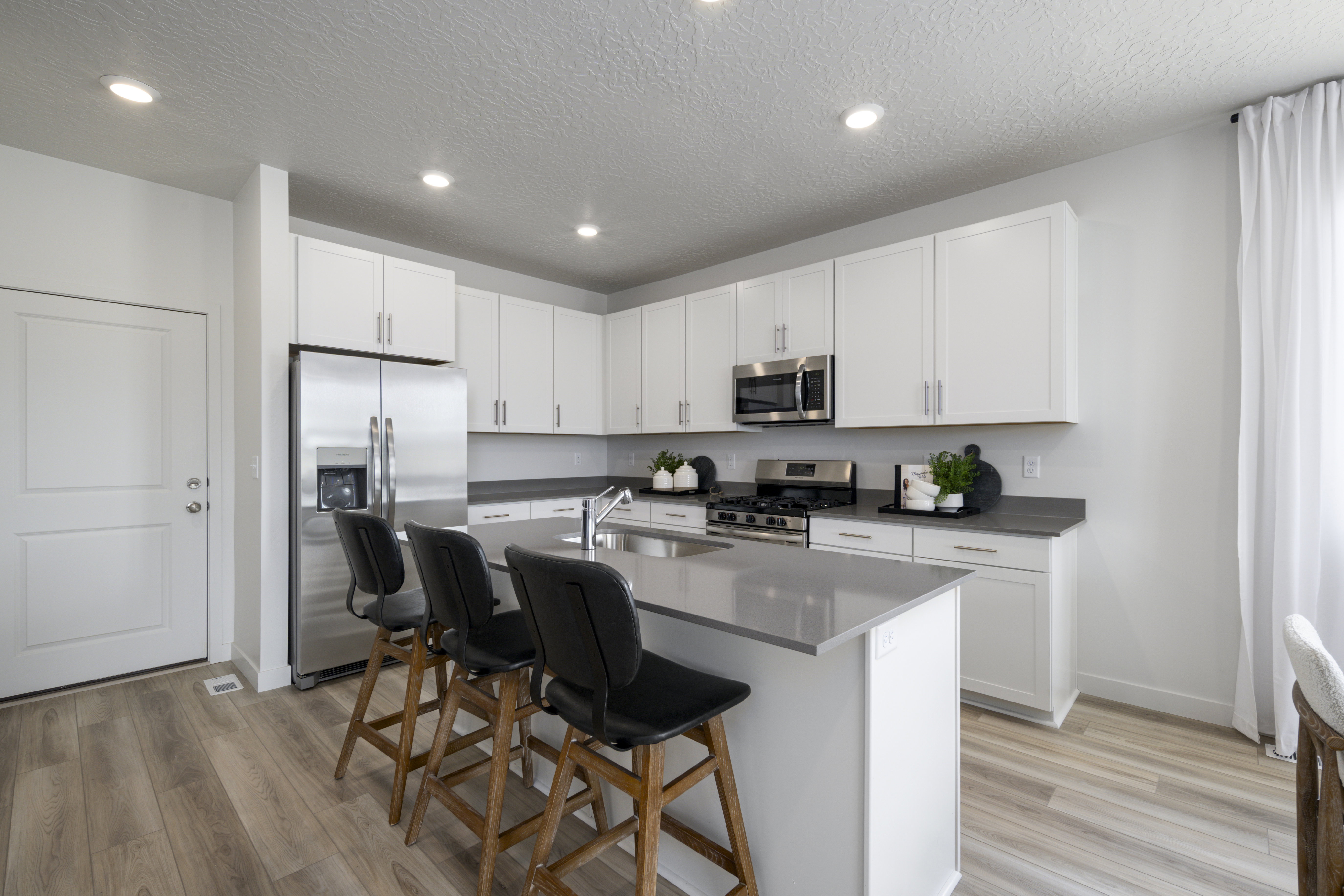 Kitchen with appliances with stainless steel finishes, a kitchen island with sink, white cabinets, a kitchen bar, and recessed lighting