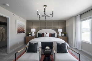 Carpeted bedroom with a textured ceiling, a walk in closet, and a chandelier