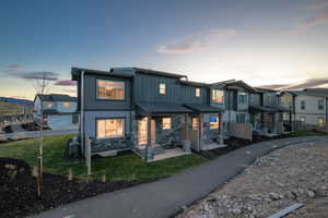 View of front facade featuring board and batten siding, a lawn, stone siding, a residential view, and covered porch
