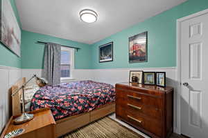 Bedroom with a wainscoted wall and a textured wall
