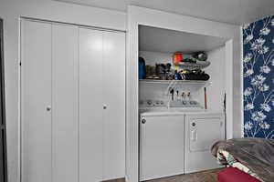 Laundry area with washer and dryer and a textured wall