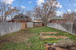 Fenced backyard featuring a deck and a storage shed