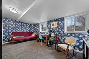 Sitting room featuring a textured ceiling, wallpapered walls, and carpet flooring