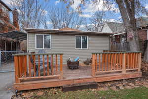Rear view of property with a deck, a detached carport, and roof with shingles