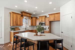 Kitchen with a breakfast bar area, dark wood-style flooring, a center island, and recessed lighting