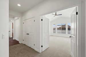 Corridor with light colored carpet, lofted ceiling, and recessed lighting into Primary Bedroom