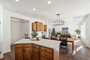 Kitchen with brown cabinets, a center island, dark wood-type flooring, hanging light fixtures, and recessed lighting