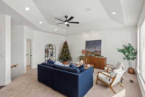 Carpeted living area featuring a tray ceiling, a ceiling fan, and recessed lighting