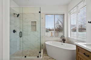 Bathroom with a freestanding tub, a marble finish shower, and vanity