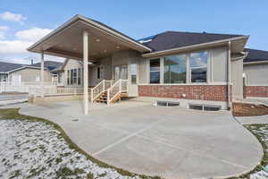 View of front of home featuring a patio, stucco siding, brick siding, and a shingled roof
