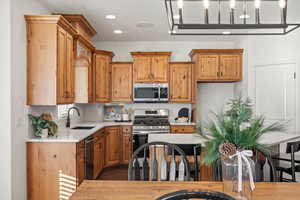 Kitchen with appliances with stainless steel finishes, light stone counters, brown cabinetry, recessed lighting, and dark wood finished floors