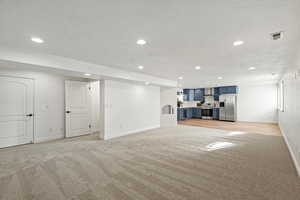 Unfurnished living room featuring light colored carpet, a textured ceiling, and recessed lighting