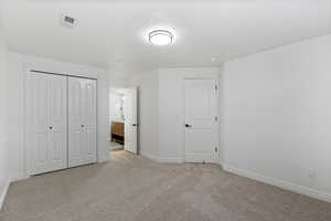 Unfurnished bedroom with connected bathroom, carpet floors, a textured ceiling, and a closet