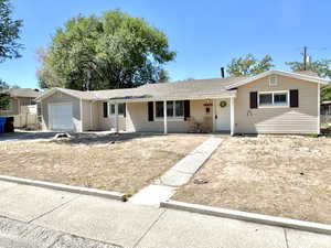 Single story home with roof with shingles, an attached garage, and covered porch