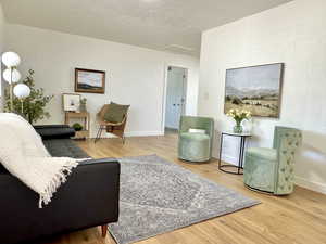 Living room with light wood-style flooring, attic access, and a textured ceiling