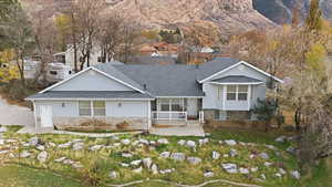 View of front of house with stone siding, roof with shingles, and a mountain view