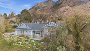 View of house featuring a mountain view, stone siding, and a shingled roof