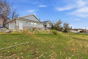 View of of home with stone siding, a yard, and an attached garage